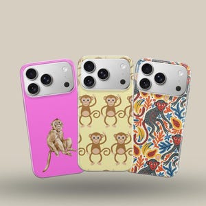 May include: Three smartphone cases featuring monkey designs. The left case is solid pink with a single monkey illustration. The center case has a light yellow background with a repeating monkey pattern. The right case features a dense jungle print.