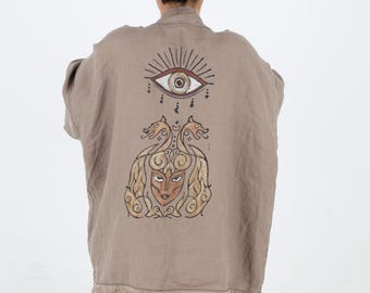 May include: A brown linen kimono with a fringed hem features a hand-painted design on the back. The design includes a large eye with rays of light, two mythical creatures with a human face, and intricate patterns.