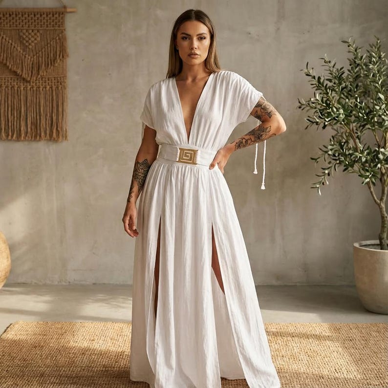 May include: A white maxi dress with a plunging neckline and short sleeves. The dress features a gold-colored buckle belt and high slits on the sides. The dress is made of a lightweight fabric, perfect for warm weather.