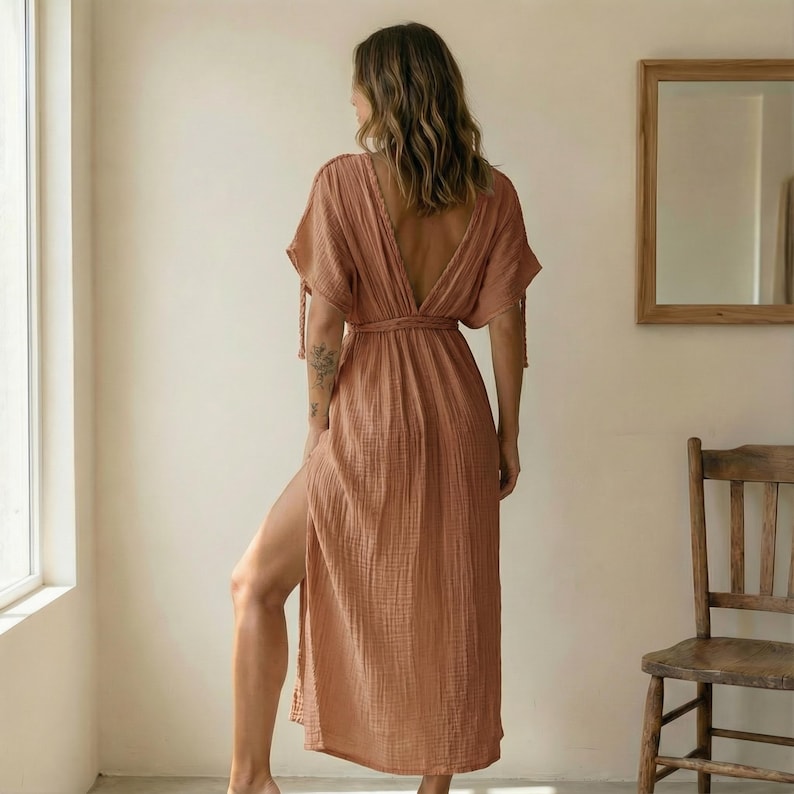 Puede incluir: Un vestido fluido de color melocot&oacute;n con cuello en V profundo y mangas cortas. El vestido presenta una cinturilla y una abertura alta en un lado. La tela parece ser un material ligero y texturizado, adecuado para climas c&aacute;lidos. El vestido es una prenda casual pero elegante.