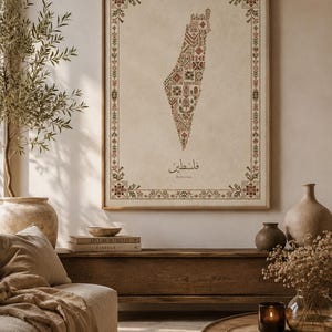 Könnte beinhalten: Ein gerahmter Kunstdruck mit einer Landkarte von Palästina, die mit komplexen roten, grünen und braunen Kreuzstichmustern gefüllt ist. Die Karte ist von einer dekorativen floralen Bordüre in ähnlichen Farben umgeben, mit dem Text Palestine und Arabisch.