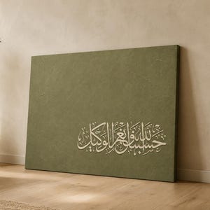 May include: A rectangular canvas wall art piece featuring a solid olive green background with a textured finish. The centre-right portion displays white Arabic calligraphy script that reads Hasbunallahu wa ni'mal wakil.