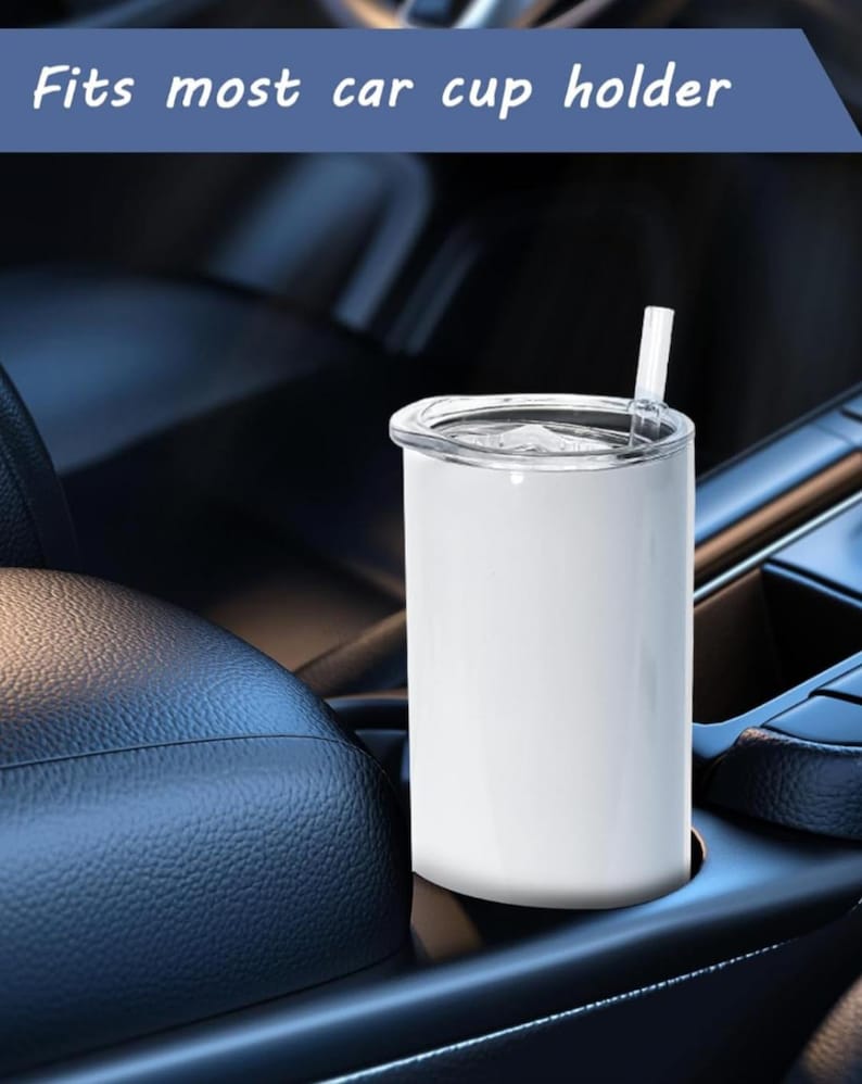 May include: A white tumbler with a clear lid and straw sits in a car cup holder. The text "Fits most car cup holder" is above the tumbler. The tumbler is cylindrical and appears to be made of metal.