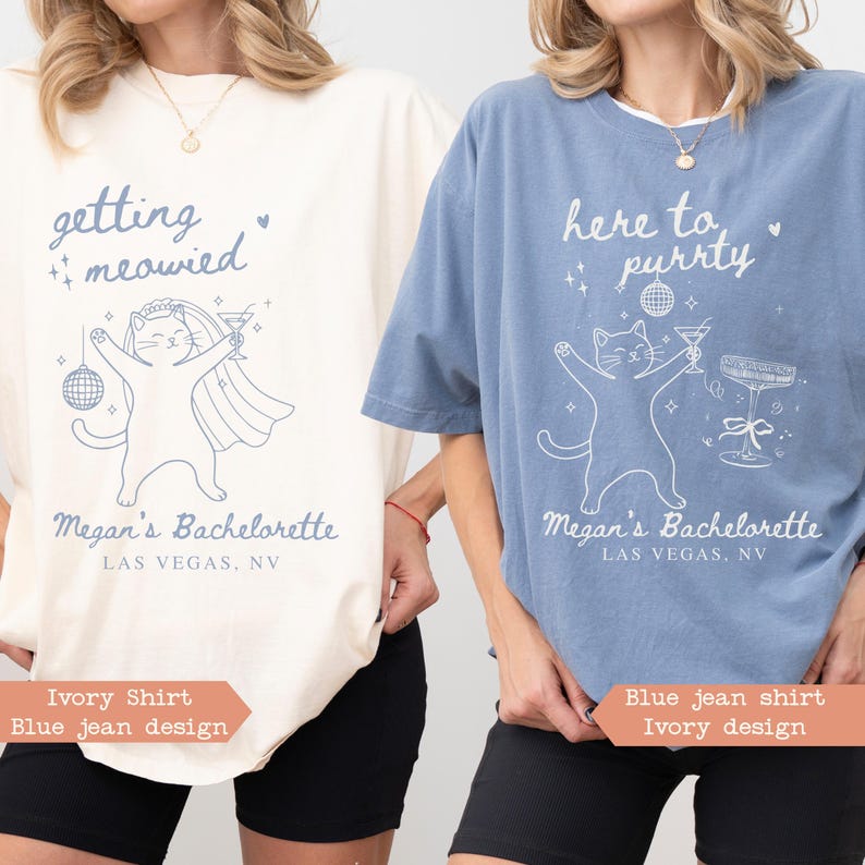 May include: Two t-shirts, one ivory and one blue, with cat-themed bachelorette party graphics. The ivory shirt says "getting meowied" and the blue shirt says "here to purrty". Both shirts feature a cat illustration and "Megan's Bachelorette, Las Vegas, NV".