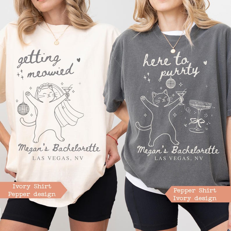 May include: Two t-shirts with cat graphics and text. One ivory shirt says "getting meowied" and the other pepper shirt says "here to purrty". Both shirts have "Megan's Bachelorette, Las Vegas, NV" printed below the cat design.