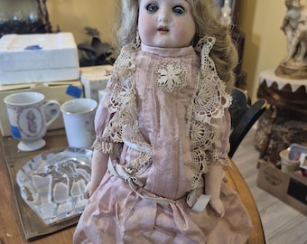 Antique german bisque doll from the early 1900s. Has its own display stand pink dress 13 inches  tall . Very good condition