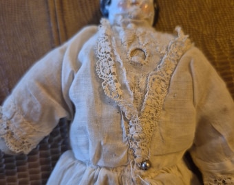 Small antique porcelain head doll from the 1870s. Cloth dress 12 inches tall