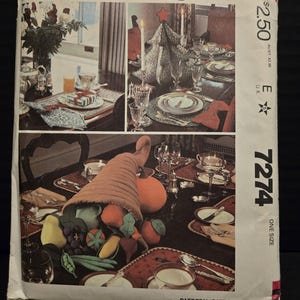 May include: A vintage McCall's sewing pattern for a cornucopia centerpiece. The pattern is for a one-size cornucopia filled with fabric fruits and vegetables. The pattern cover shows three different table settings with the cornucopia centerpiece.