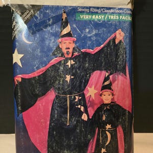 May include: A vintage sewing pattern for a wizard costume. The pattern includes instructions for making a long black robe with a pink cape, a pointed hat, and a star design. The pattern is labeled "Butterick 5873" and is rated "Very Easy/Tres Facile".