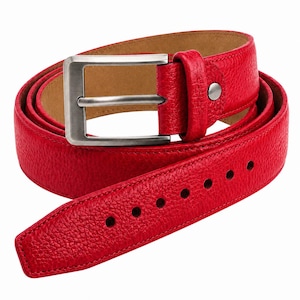 Peut inclure: Une ceinture rouge vif avec une surface texturée et grainée et une doublure intérieure beige. La ceinture présente une boucle rectangulaire en métal argenté brossé et un passant en cuir rouge assorti fixé par un petit rivet en métal argenté.