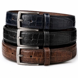 May include: A stack of three belts featuring a textured crocodile-embossed pattern. The belts are coloured in navy blue, black, and brown. Each belt includes a rectangular brushed silver-tone metal buckle, a matching leather keeper loop, and pre-punched holes.
