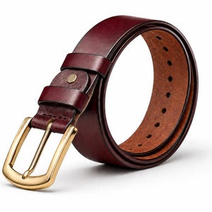 May include: A burgundy leather belt with a gold-colored buckle. The belt has a classic design with a rectangular buckle and a series of evenly spaced holes. The leather appears smooth and has a rich, deep color.
