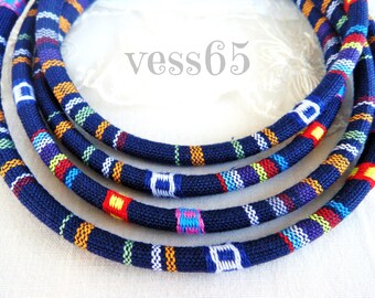 May include: Four strands of navy blue fabric cord with colorful woven patterns. The cord is twisted and layered, creating a textured look.