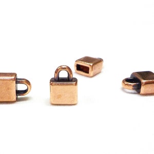 Puede incluir: Tres tapones de metal de color cobre para cordón o correas de cuero. Un tapón tiene forma de candado con un bucle cerrado. Los otros dos tapones son cuadrados con una pequeña abertura.