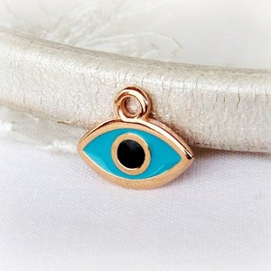 Puede incluir: Encanto de tono dorado con un dise&ntilde;o de ojo azul malvado. El ojo est&aacute; rodeado por un borde de tono dorado y tiene una pupila negra.