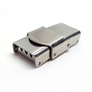 May include: A silver metal clasp with a serrated edge and a hinged closure.