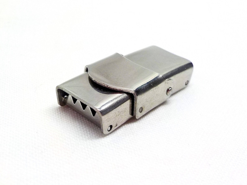 May include: A silver metal clasp with a serrated edge and a hinged closure.