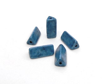 May include: Five blue ceramic triangle beads with a hole in the center of each bead.
