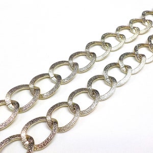 May include: A gold chain with oval links. The chain is made of metal and has a textured finish.