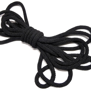 May include: A black rope cord, coiled and twisted, with a rough texture. The cord is thick and durable, suitable for various crafting and decorative projects.