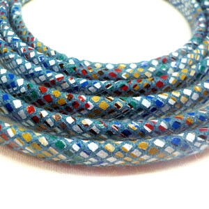 May include: A close-up of a blue cord with a colorful, patterned design. The cord is made of a soft, textured material and has a subtle sheen.