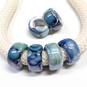 May include: Six blue and white marbled ceramic beads with a white rope threaded through them.