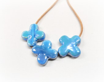 May include: A necklace with three blue iridescent flower-shaped beads on a brown leather cord.