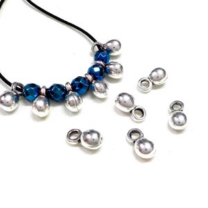 May include: A necklace with blue and silver beads, with additional silver beads on a white background.