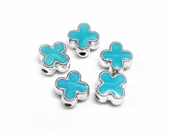 Puede incluir: Seis cuentas de color azul turquesa en forma de flor con detalles en metal plateado. Las cuentas tienen un acabado brillante.