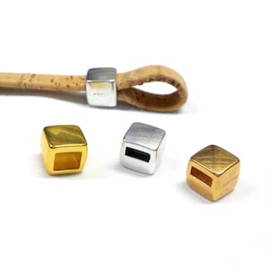 Könnte beinhalten: Drei Metall-Schnallen in Gold und Silber. Die Schnallen sind quadratisch mit einem kleinen Loch in der Mitte.