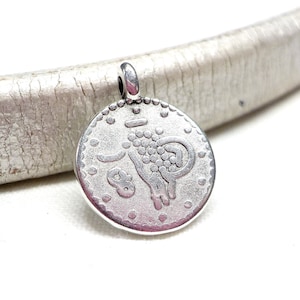 May include: Silver charm with a detailed design of a ram or goat. The charm has a loop at the top for attaching to a necklace or bracelet.