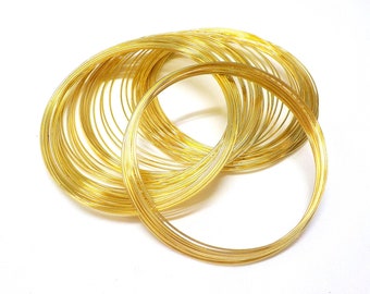 May include: A pile of gold-colored wire rings, stacked and overlapping. The rings are made of thin wire and are all the same size.