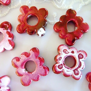Puede incluir: Un conjunto de ocho cuentas de cer&aacute;mica de color rojo y blanco con forma de flor y un agujero en el centro. Las cuentas tienen un acabado brillante y son perfectas para hacer joyas o manualidades.