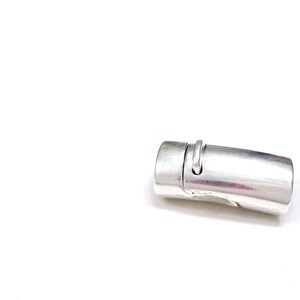 May include: A silver-colored magnetic clasp, designed for jewelry making. The clasp is cylindrical with a curved design and a small loop. It is shown against a white background.