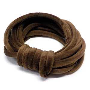 Può includere: Un cordoncino di velluto marrone arrotolato in un cerchio. Il cordoncino è morbido e vellutato, ideale per progetti di artigianato.