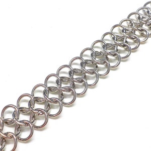 May include: A silver chainmail bracelet with a woven pattern.