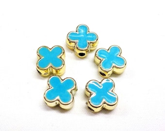 May include: Five gold-colored metal flower-shaped beads with a turquoise blue enamel finish. The beads have four petals and a hole in the center.