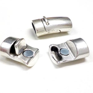 May include: Three silver-colored magnetic clasps for jewelry making. The clasps have a rectangular shape with a curved design and a small magnet. The clasps are shown against a white background.