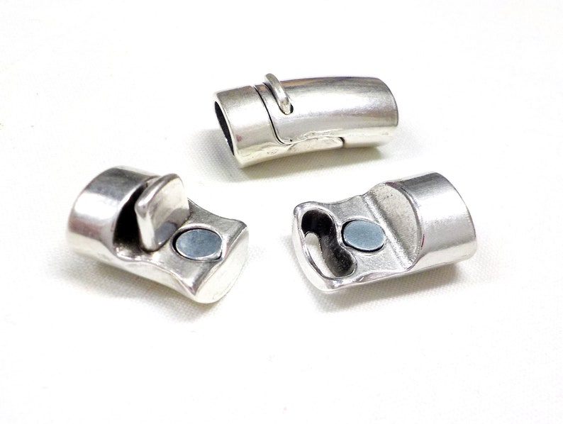 May include: Three silver-colored magnetic clasps for jewelry making. The clasps have a rectangular shape with a curved design and a small magnet. The clasps are shown against a white background.