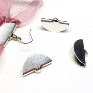 Op de afbeelding: Drie zilveren metalen halfronde oorbelsluitingen. De sluitingen hebben een kleine lus aan de bovenkant om aan een oorhaak te bevestigen.