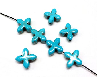 May include: Seven turquoise blue flower-shaped beads with a distressed finish. The beads are strung on a black cord.