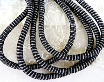May include: Black and white striped cord, twisted together in a decorative pattern. The cord is thick and has a soft texture.