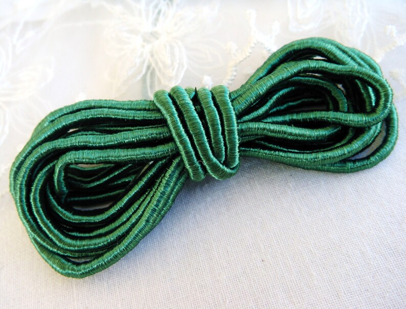May include: A spool of dark green elastic cord. The cord is tightly wound and has a smooth, shiny finish.