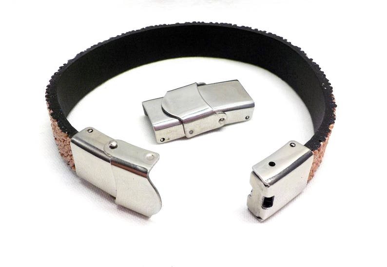 May include: A close-up of a brown leather bracelet with silver metal clasps. The bracelet is open and the clasps are visible.
