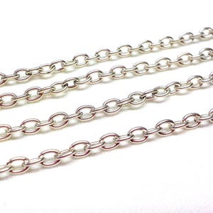 May include: A close-up of four silver chains, each with a different length. The chains are made of oval-shaped links.