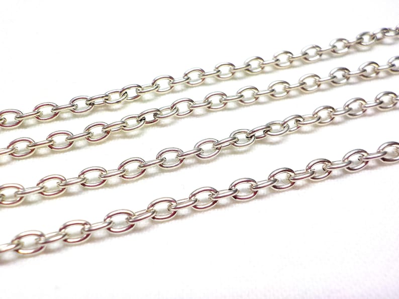 May include: A close-up of four silver chains, each with a different length. The chains are made of oval-shaped links.