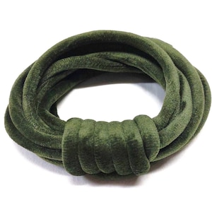 May include: An olive green velvet hair tie, knotted in a circular shape. The hair accessory is made of a soft, plush material and is set against a white background. The hair tie is a stylish accessory.