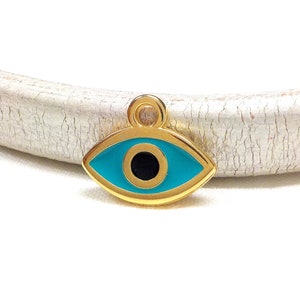 May include: Gold charm with a blue evil eye design. The eye is surrounded by a gold frame and has a black pupil.