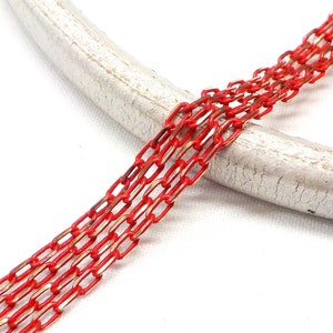 K&ouml;nnte beinhalten: Rote und goldene Kette mit flachem, rechteckigem Glieddesign. Die Kette liegt auf einer wei&szlig;en Oberfl&auml;che.