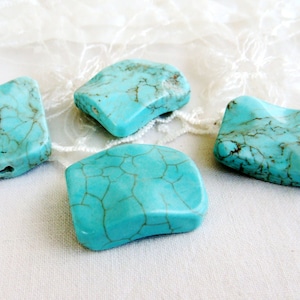 Peut inclure: Quatre pierres lisses de forme irrégulière de couleur bleu turquoise avec un motif marbré. Les pierres sont sur un fond blanc.